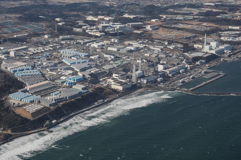 This aerial picture taken by Jiji Press on February 14, 2021 shows a view of TEPCO's crippled Fukushima Daiichi Nuclear Power Plant as well as tanks (L) used for storing treated wastewater, along the coast in Okuma, Fukushima prefecture