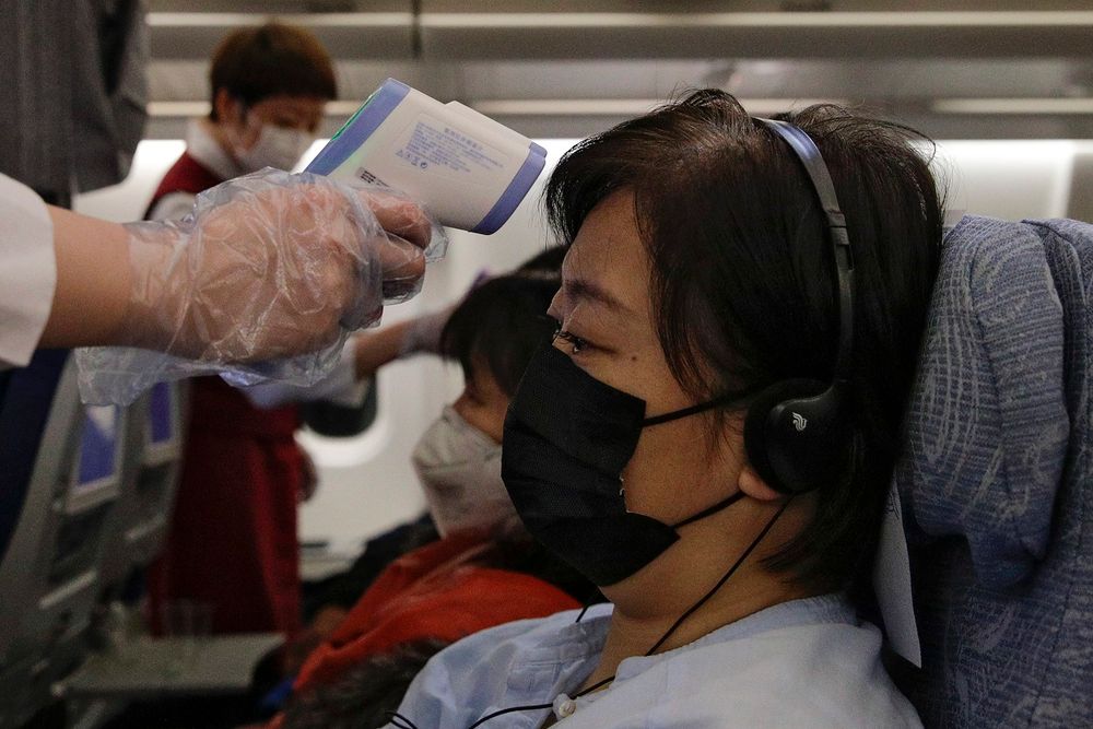 Stewardesses take temperatures of passengers as a preventive measure for the coronavirus on an Air China flight from Melbourne to Beijing before it land at Beijing Capital International Airport in China, Tuesday, Feb. 4, 2020
