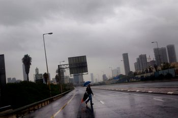 FILE: A person crosses the blocked and flooded Ayalon freeway in Tel Aviv, as heavy rains flooded Tel Aviv