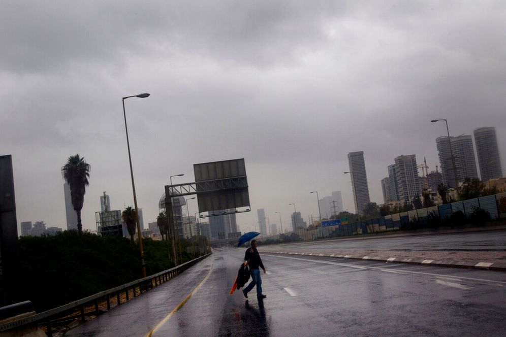 FILE: A person crosses the blocked and flooded Ayalon freeway in Tel Aviv, as heavy rains flooded Tel Aviv