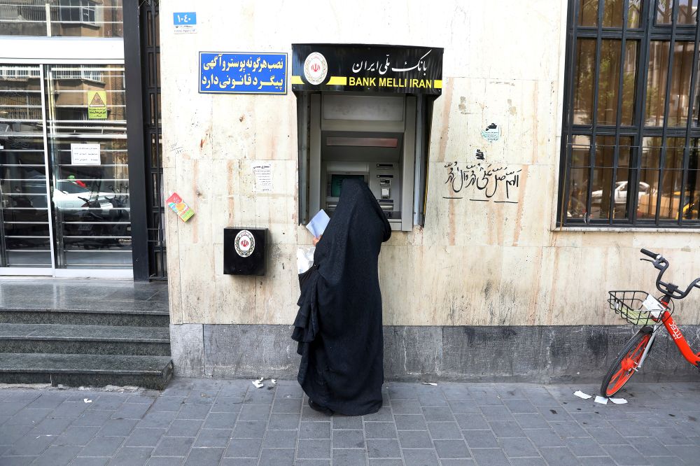 A woman uses an ATM machine at a branch of the Bank Melli Iran, at the Grand Bazaar of Tehran, Iran,