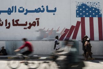 Taliban members walk past a mural depicting a US flag on the first anniversary of the withdrawal of foreign troops from Afghanistan, in Kabul, on August 31, 2022.