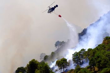 A helicopter launches water as a wildfire advances near a residential area in Alhaurin de la Torre, Malaga, Spain, on July 16, 2022.