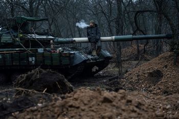 A Ukrainian serviceman smokes a cigarette standing atop a tank near Bakhmut, Ukraine.
