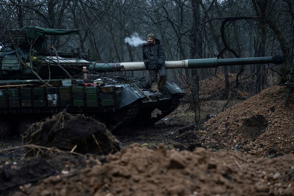 A Ukrainian serviceman smokes a cigarette standing atop a tank near Bakhmut, Ukraine.