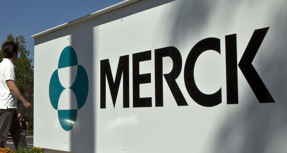 Sur cette photo d'archive prise le 2 octobre 2013, des employés de la société pharmaceutique Merck passent devant un panneau devant le bâtiment de la société dans le New Jersey.