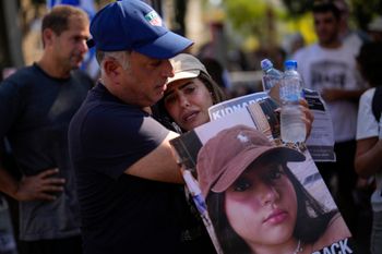 Eli, left, and Shira, parents of Liri Albag hold her photograph as they gather with others during a protest demanding the release of dozens of Israelis who have been abducted during last week's unprecedented Hamas attack, in Tel Aviv