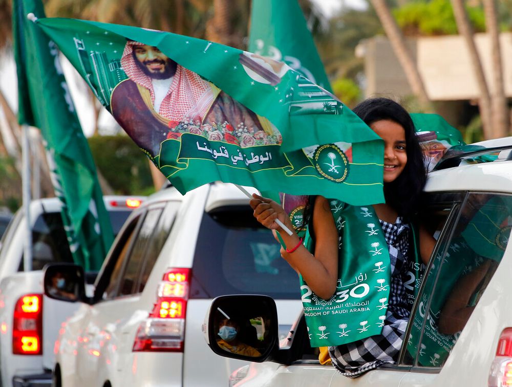 In this photo, a Saudi girl waves a national flag with a picture of Saudi Crown Prince Mohammed bin Salman during celebrations marking National Day to commemorate the unification of the country as the Kingdom of Saudi Arabia, in Jeddah, Saudi Arabia.