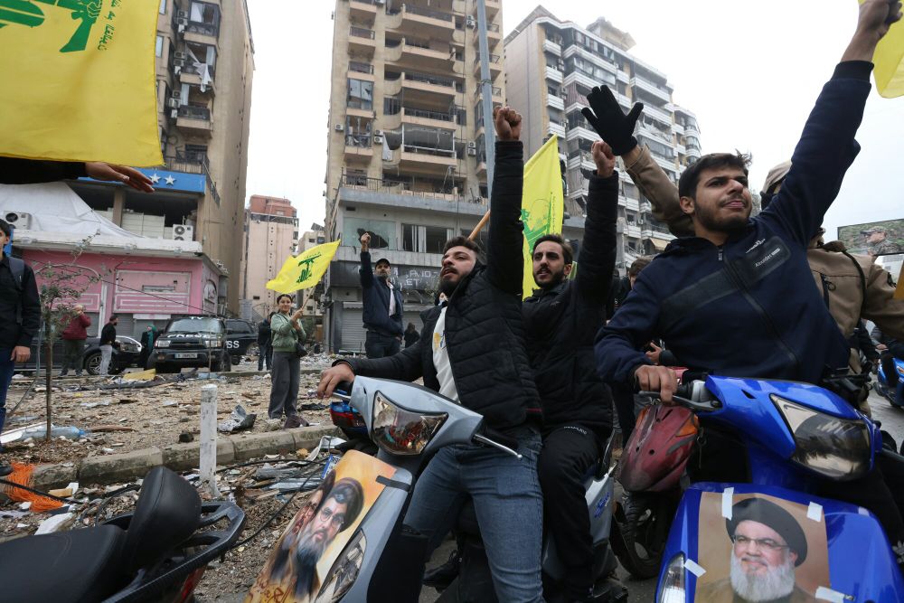 Hezbollah supporters wave flags and hold pictures of the former secretary general – Hassan Nasrallah, who was killed in an IDF strike in Beirut – as they return to the southern Dahieh neighborhood after a ceasefire went in effect