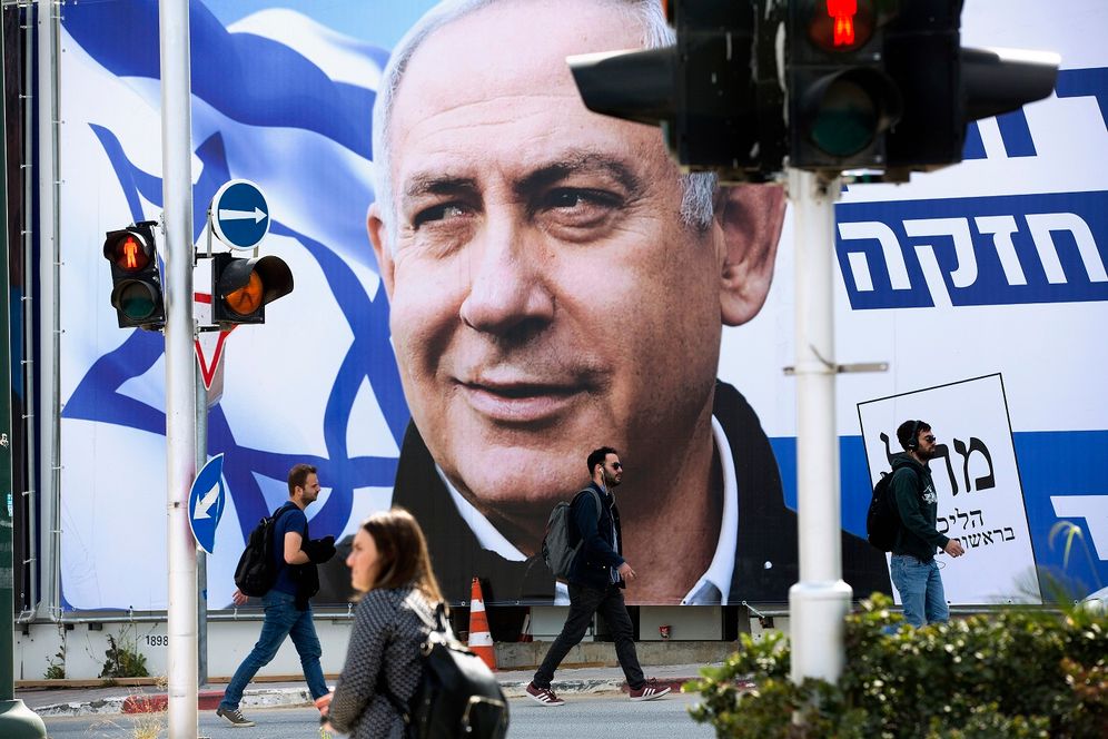 People walk by an election campaign billboard showing Israel's Prime Minister Benjamin Netanyahu, the Likud party leader, in Tel Aviv, Israel, Thursday, March 28, 2019.