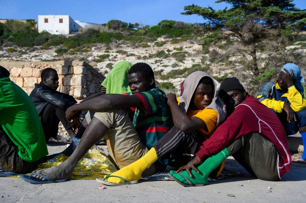 Migrants sit in Lampedusa Island, Italy.
