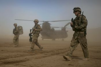U.S. soldiers part of the NATO- led International Security Assistance Force (ISAF) walks, as a U.S. Chinook helicopter is seen on the back ground near the place where the foundation of a hospital was laid in Shindand, Herat, west of Kabul, Afghanistan, Saturday, Jan. 28, 2012.
