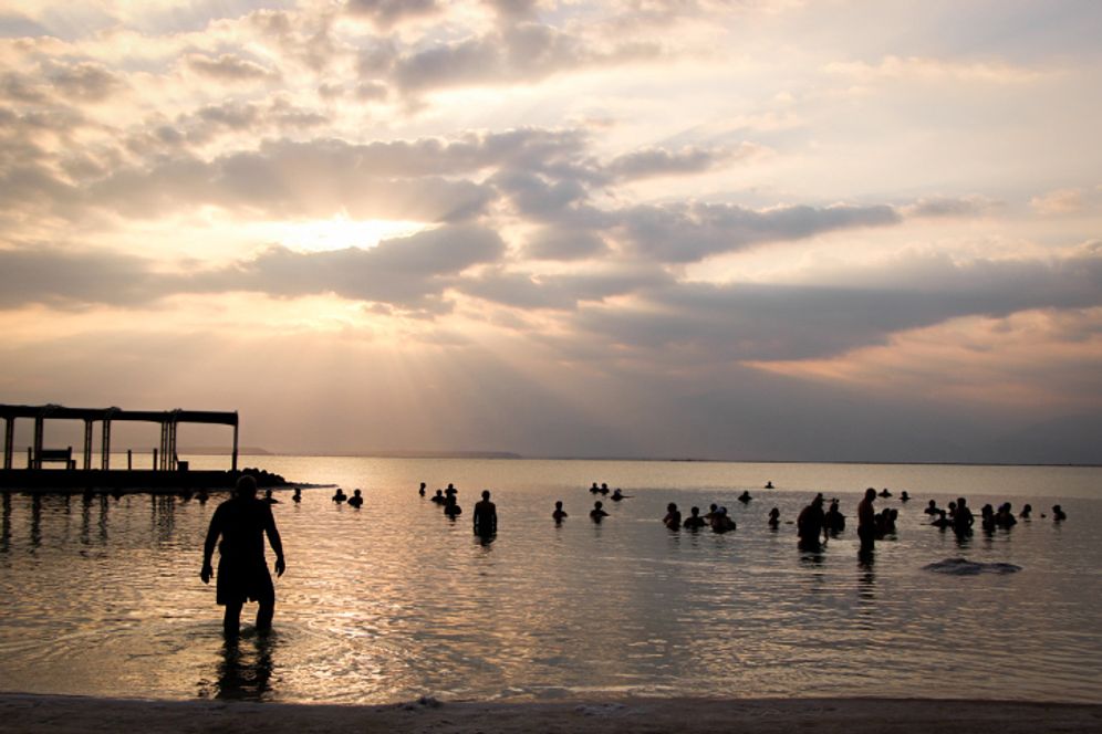 Gershon Elinson/Flash90 People swimming in the Dead Sea as the sun rises over the hills in Israel.