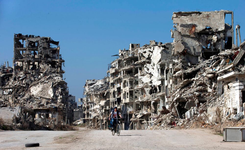 A Syrian boy rides a bicycle through a devastated part of the old city of Homs, Syria, on February 26, 2016.