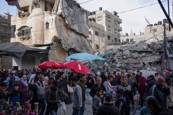 Des Palestiniens achètent de la nourriture sur un marché local à côté d'un immeuble résidentiel détruit par les frappes aériennes israéliennes, pendant le Ramadan, à Rafah, dans la bande de Gaza, le jeudi 14 mars 2024.