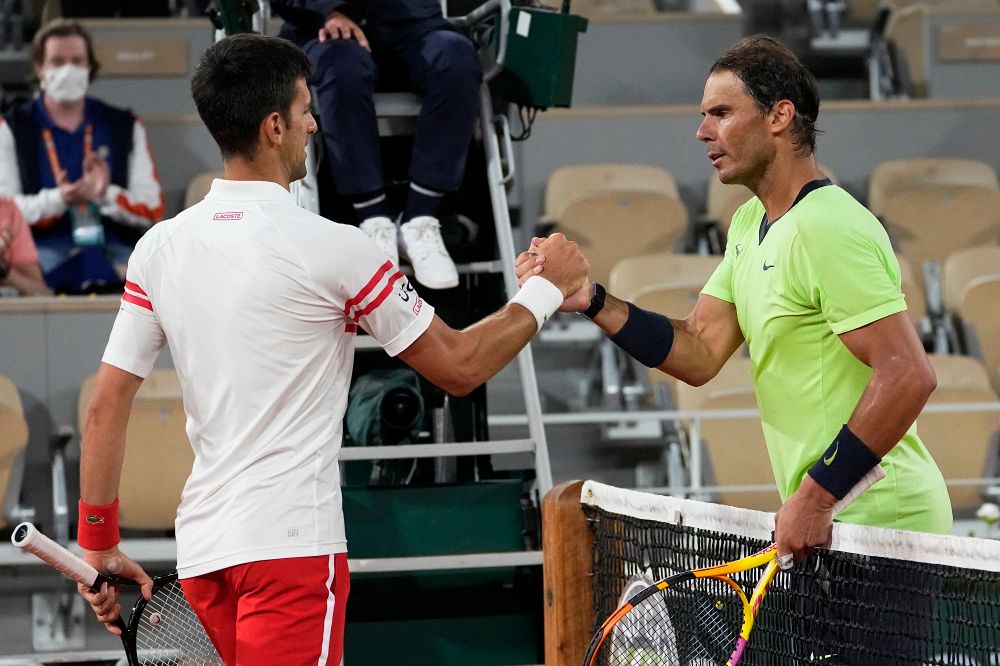 Serbia's Novak Djokovic, (L), shakes hands with Spain's Rafael Nadal after their semifinal match of the French Open tennis tournament at the Roland Garros stadium, June 11, 2021 in Paris.