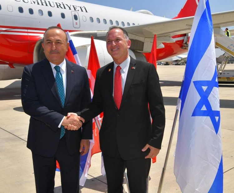 Turkey's Foreign Minister Mevlut Cavusoglu, (L), is greeted by Israel's Master of Ceremonies Gilad Adin at Ben Gurion Airport on May 24, 2022.
