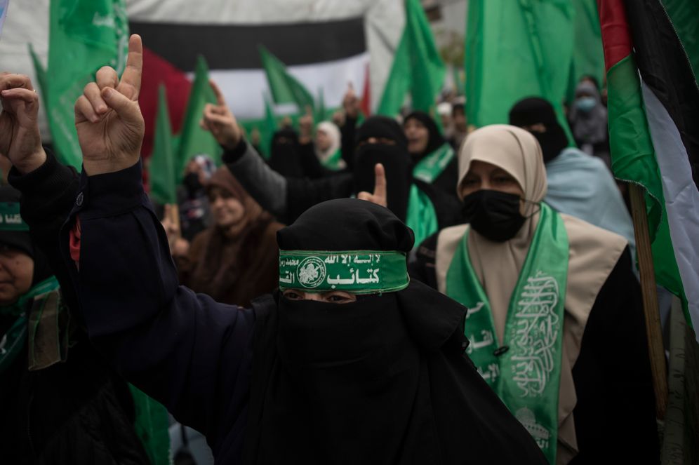A Palestinian woman with a green head band with Arabic writing that reads "Qassam Brigades" chants Islamic slogans as she attends a rally in Gaza City