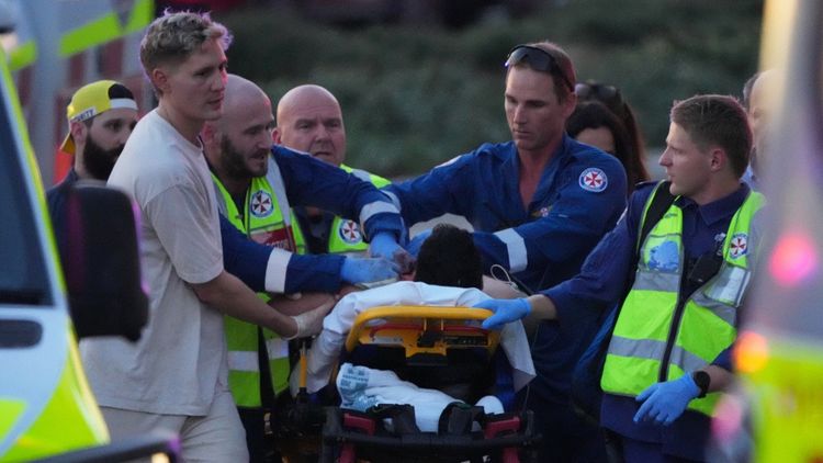 Emergency workers transport a person on a stretcher after a reported shooting at Bondi Beach, in Sydney, Sunday, Dec. 14, 2025