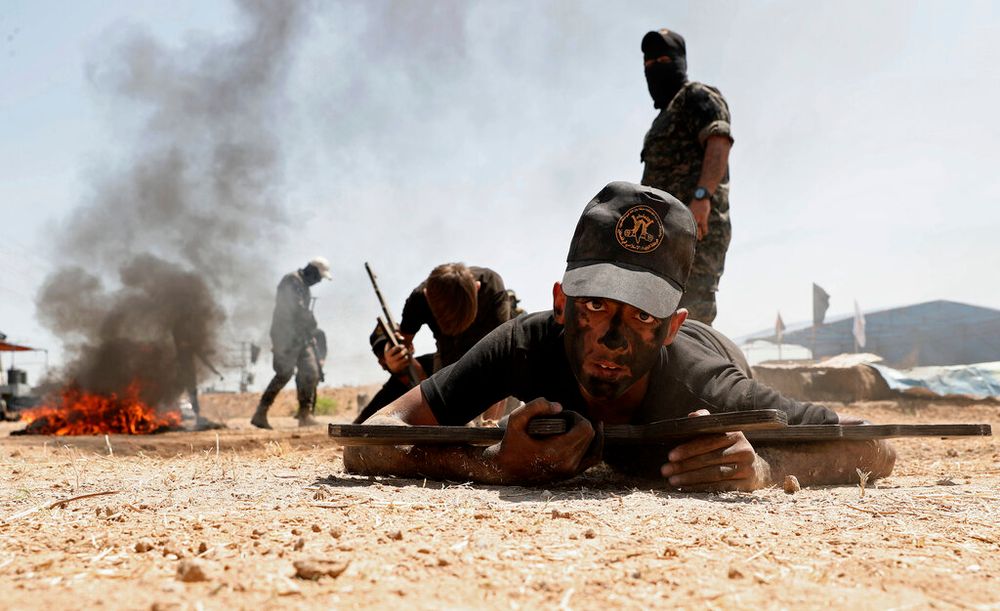 Youths crawl while holding wooden mock rifles during a military summer training camp organized by the Palestinian Islamic Jihad group, in Gaza City, Gaza, on June 28, 2021.