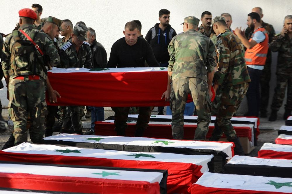 Syrian soldiers arrange caskets during the funeral of the victims of a drone attack targeting a Syrian military academy, outside a hospital in government-controlled Homs