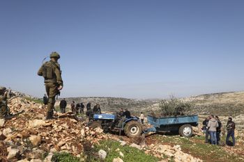 Israeli soldiers prevent settlers from approaching Palestinians near a settlement west of the Palestinian village of Salfit in the West Bank, on February 3, 2022.