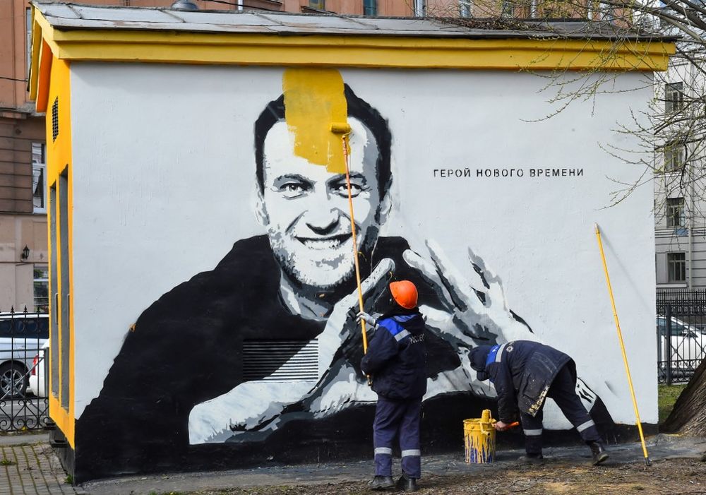 A worker paints over graffiti of jailed Kremlin critic Alexei Navalny in Saint Petersburg, which reads: "The hero of the new times," on April 28, 2021.
