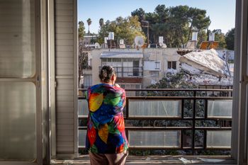 A woman looks out from her balcony at a residential building damaged by shrapnel from a ballistic missile fired from Iran in Ramat Gan, March 3, 2026