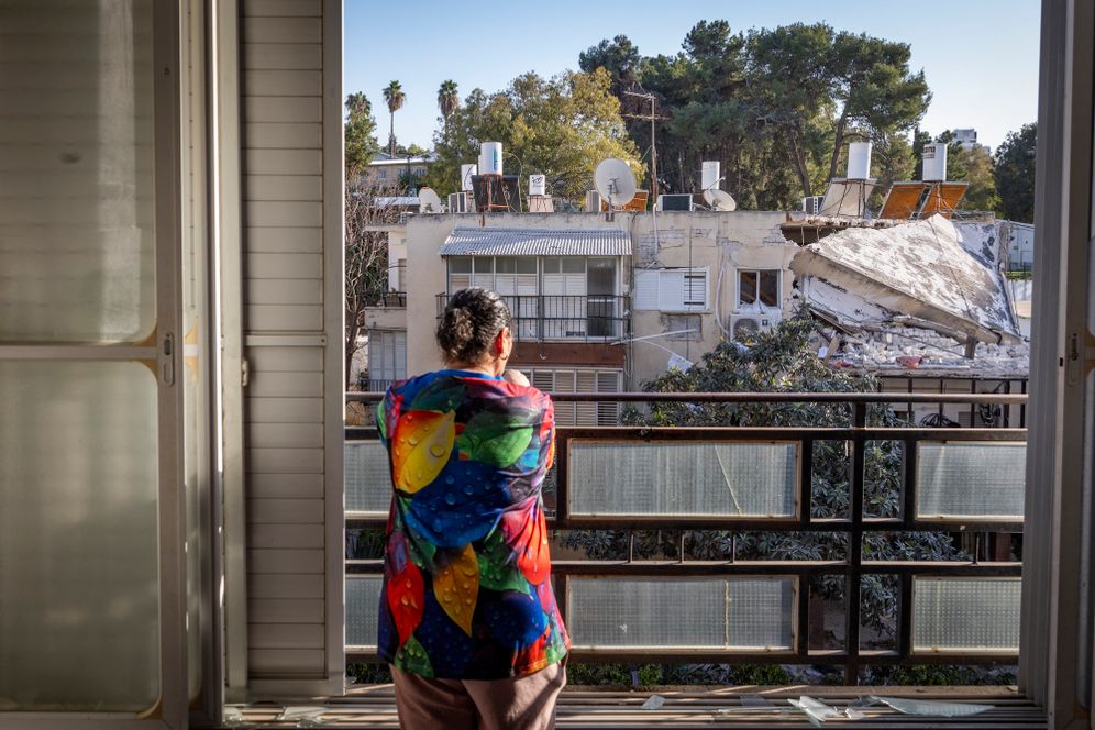 A woman looks out from her balcony at a residential building damaged by shrapnel from a ballistic missile fired from Iran in Ramat Gan, March 3, 2026