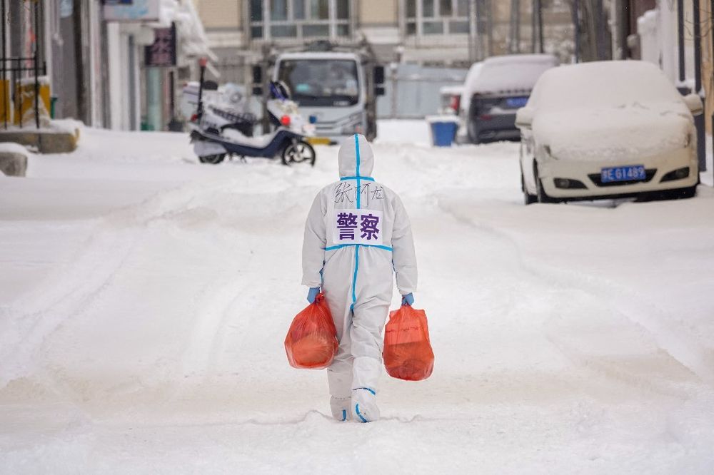 A police officer carries daily supplies that will be distributed to residents in Manzhouli of China's northern Inner Mongolia region, on March 15, 2022.