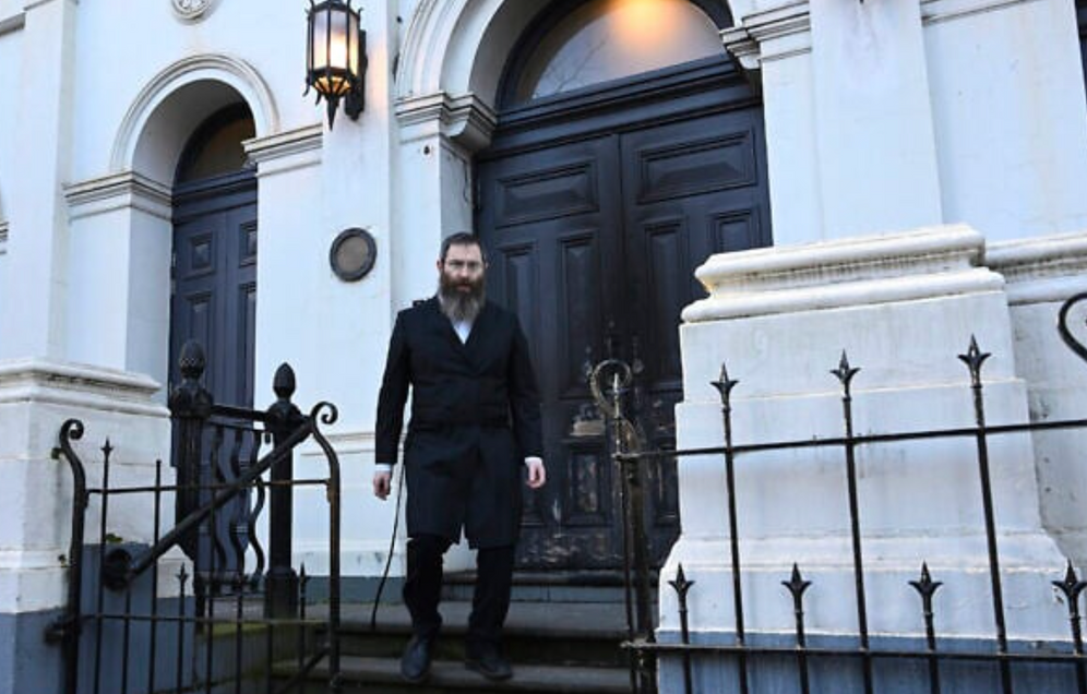 Le rabbin Dovid Gutnick passe devant les dégâts causés à l'extérieur de la Congrégation hébraïque d'East Melbourne à Melbourne, samedi 5 juillet 2025, après qu'un homme ait mis le feu à la porte.