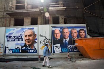 A man walks by election campaign billboards in Tel Aviv, Israel, Sunday, April 7, 2019.
