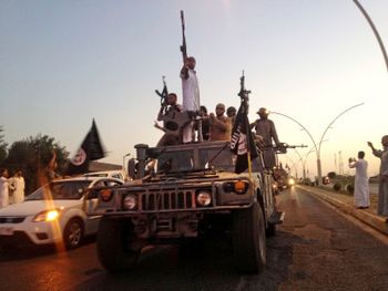 FILE - In this June 23, 2014, file photo, fighters from the Islamic State group parade in a commandeered Iraqi security forces armored vehicle in the northern city of Mosul, Iraq