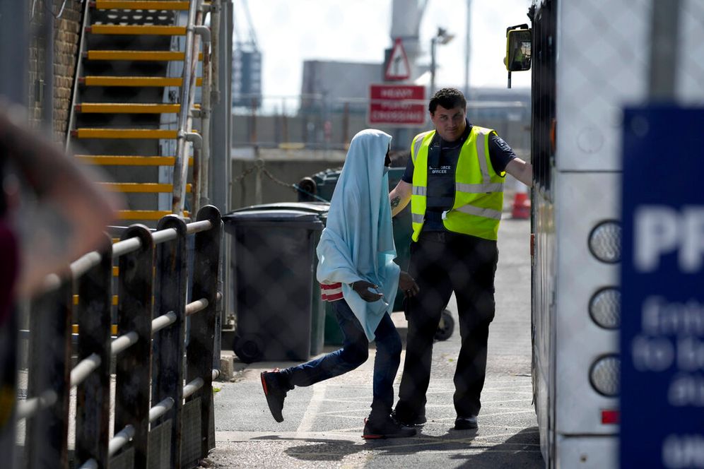 A man thought to be a migrant picked up in the English Channel is directed to board a waiting transfer bus in Dover, southeast England, on June 17, 2022.