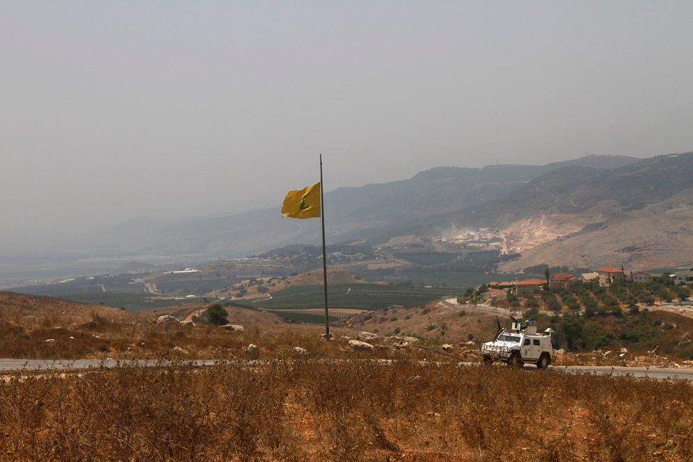 A UN vehicle manned by Spanish peacekeepers patrols near a Hezbollah flag on the Lebanese side of the Lebanese-Israeli border in the southern village of Kfar Kila, in southeast Lebanon, on July 28, 2020.