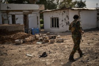 (AP Photo/Leo Correa) A member of the armed wing of the Kurdish-Iranian opposition group Organization of Iranian Kurdistan Struggle, known as Khabat, walks past an area that allegedly was damaged in a strike by Iranian-backed militias in Iraq