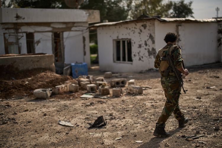 A member of the armed wing of the Kurdish-Iranian opposition group Organization of Iranian Kurdistan Struggle, known as Khabat, walks past an area that allegedly was damaged in a strike by Iranian-backed militias in Iraq