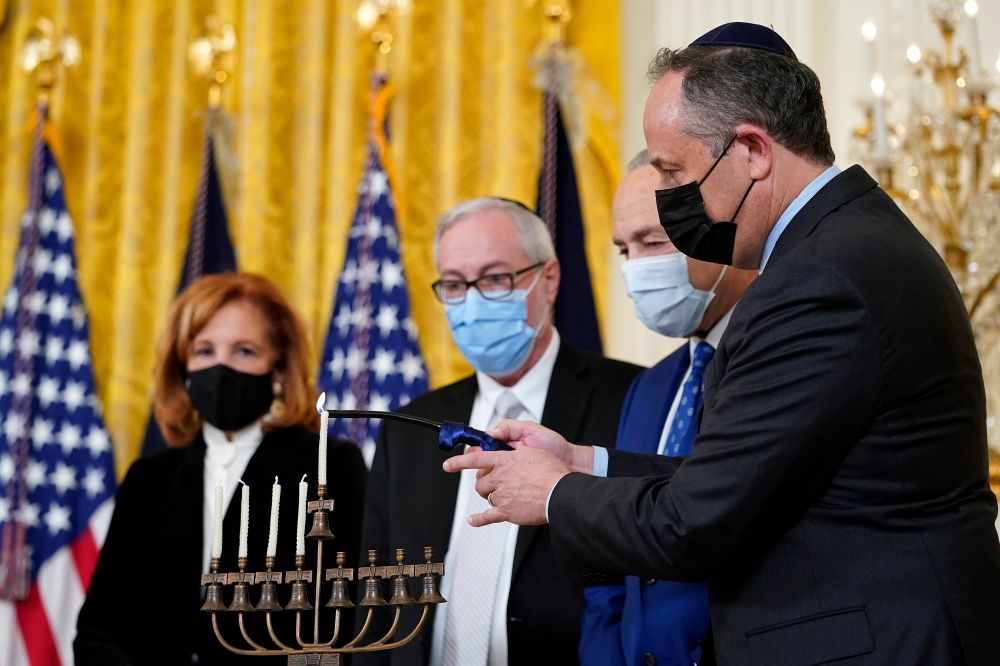 Second gentleman Doug Emhoff, (R), lights the menorah in the East Room of the White House in Washington, during an event to celebrate Hanukkah, December 1, 2021.