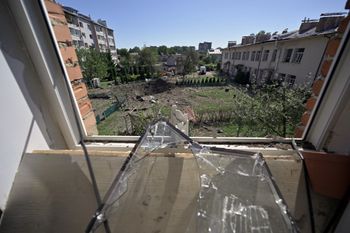 A view taken through a shattered window pane shows the crater of a missile that fell between residential buildings and a kindergarten in the city of Lviv, western Ukraine.