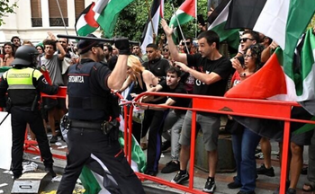 Un officier de la police régionale basque « Ertzaintza » lève une matraque alors que des manifestants pro-palestiniens et anti-israéliens brandissant des drapeaux palestiniens manifestent lors de la onzième étape du Tour d'Espagne, une course cycliste de 167 km de Bilbao à Bilbao, le 3 septembre 2025. 