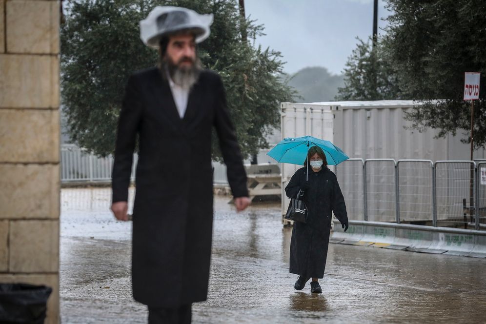 An ultra-Orthodox Jewish man walks in the rain in the northern Israeli city of Safed, on December 15, 2020.