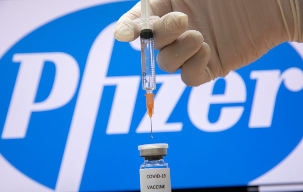 A photo illustration of a syringe and and a bottle reading "Covid-19 Vaccine" next to the Pfizer company logo in Jerusalem on December 10, 2020.