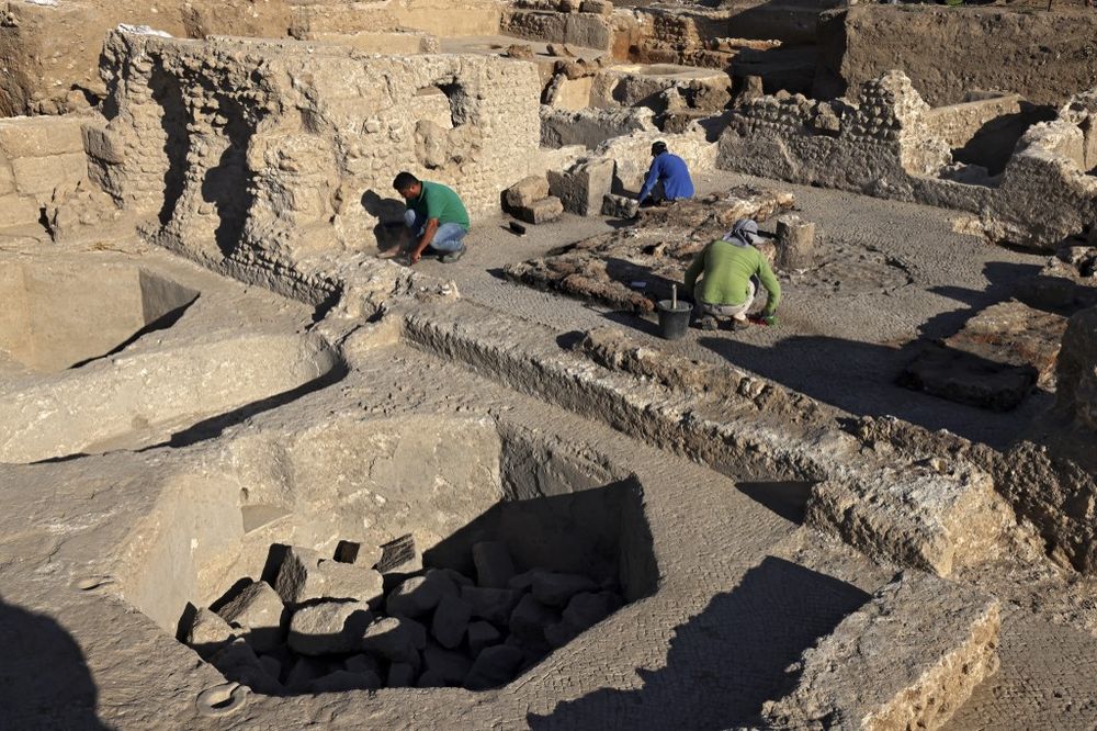 Archaeologists and technicians of the Israel Antiquities Authority excavate inside a winepress at the Tel Yavne site in central Israel on October 11, 2021.