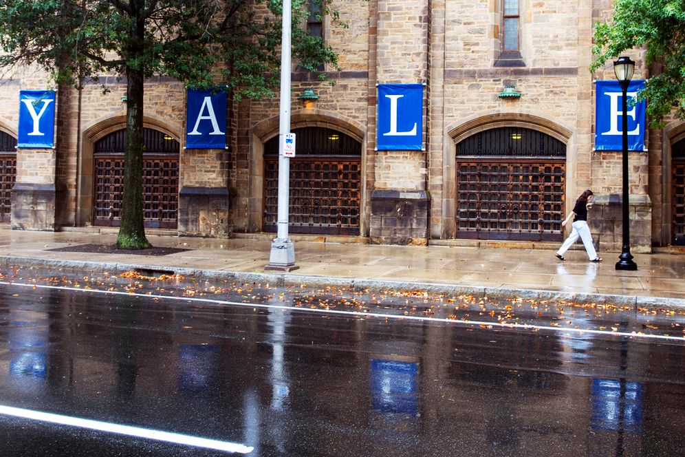 Photo/Ted Shaffrey, AP A woman walks by a Yale sign reflected in the rainwater on the Yale University campus, Aug. 22, 2021, in New Haven, Conn