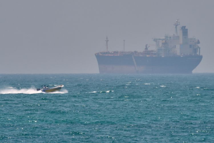 FILE - A boat sails past a tanker anchored on the Strait of Hormuz off the coast Qeshm island, Iran, April 18, 2026.