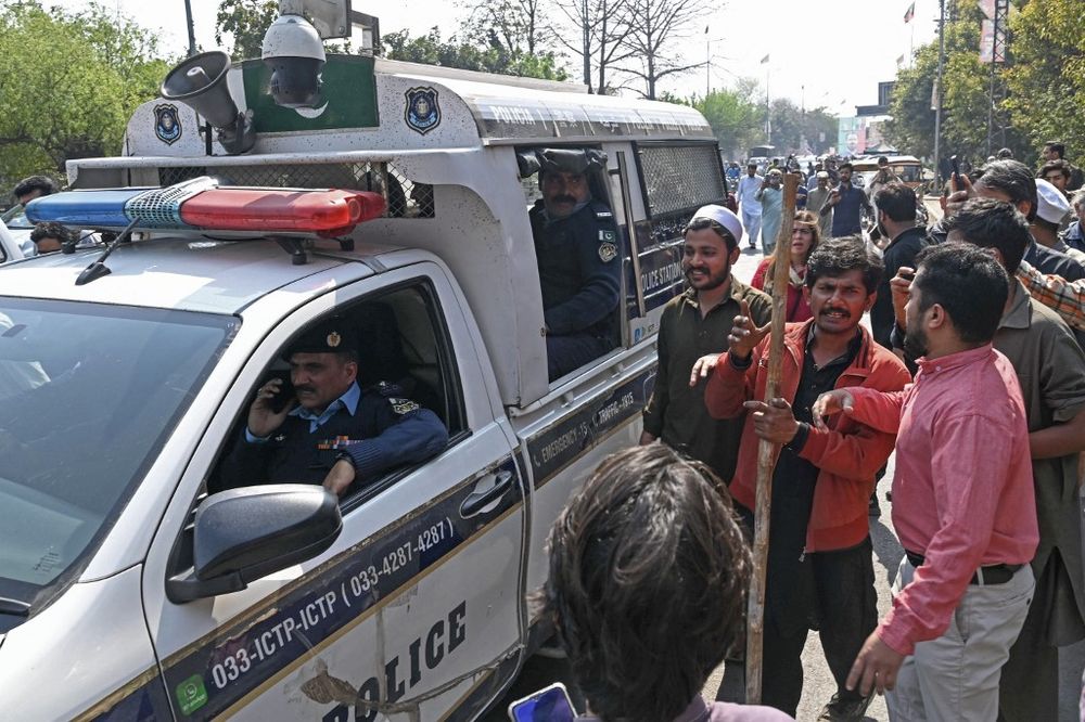People gather around a police van in Pakistan.