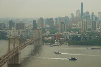 Boats maneuver the East River near the Brooklyn Bridge as smoke from wildfires blankets the sky Thursday, July 16, 2026, in New York. 
