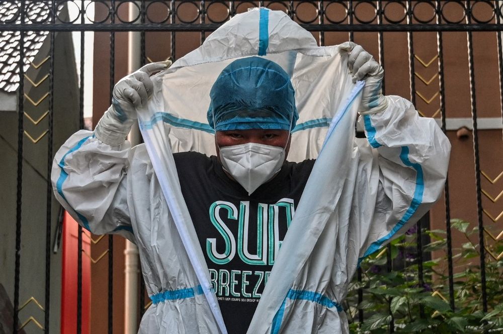 A worker takes off personal protective equipment in front of a residential area under a Covid lockdown in the Huangpu district of Shanghai, China, on June 4, 2022.