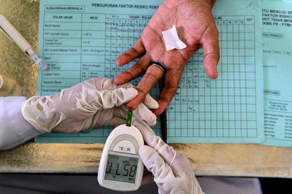 An elderly woman gets her blood tested during a drive to provide medical check-ups for diabetes at an integrated services post in Banda Aceh, Indonesia, on December 15, 2021.