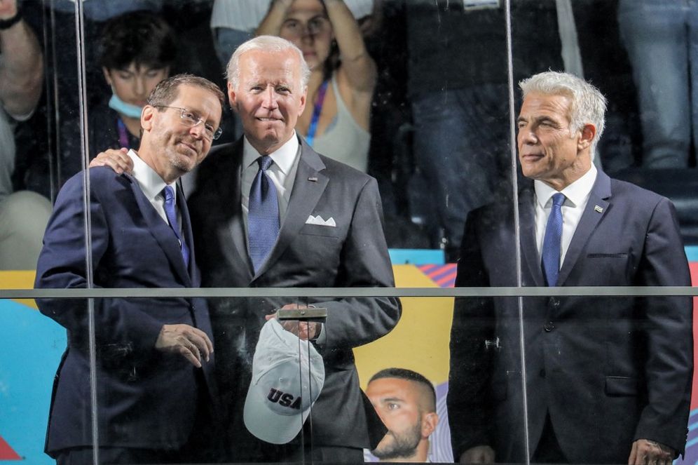 US President Joe Biden (C) embraces Israel's President Isaac Herzog (L) as Prime Minister Yair Lapid looks on during the opening ceremony of the Maccabiah Games at Teddy Stadium in Jerusalem, on July 14, 2022.